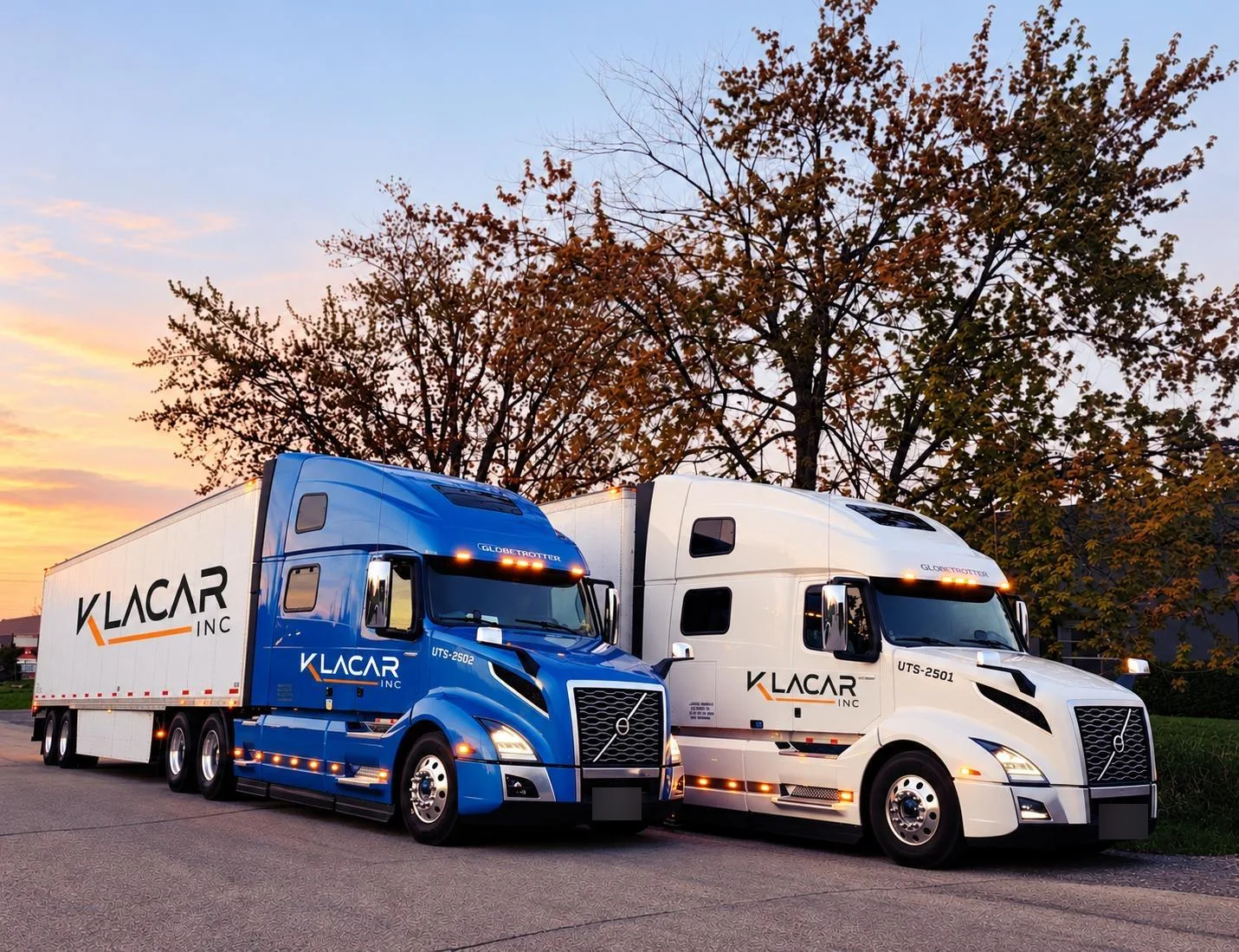 Klacar tractor-trailers parked side by side at sunset