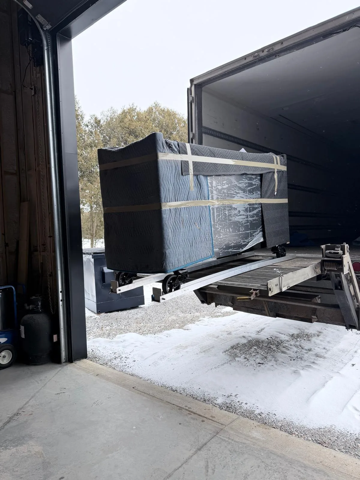 A wrapped item on a Klacar liftgate in winter